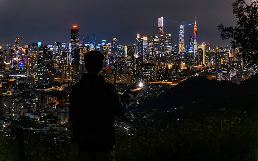 A figure reaching towards the skyline under bright city illumination